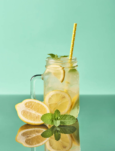 Fresh tasty lemonade in mason jar glass on turquoise background - Photo, Image
