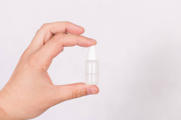 A small tube with a colorless liquid in a hand on a white background - Photo, Image
