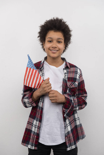 Веселый позитивный мальчик, стоящий с флагом США
 - Фото, изображение