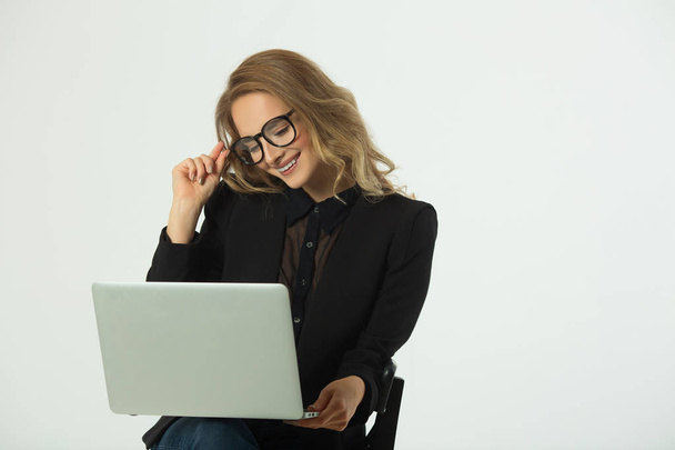 beautiful young girl with glasses in a black suit with a laptop on a white background - Fotografie, Obrázek