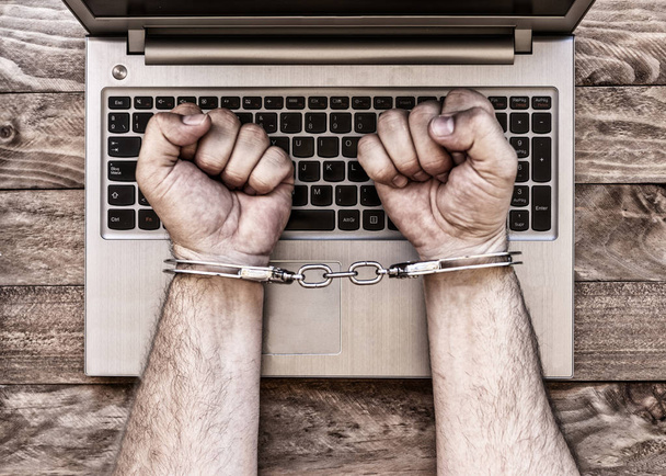 Handcuffed hands with laptop. - Fotoğraf, Görsel