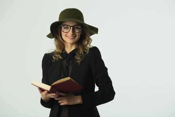 kaunis nuori tyttö lasit ja hattu lukeminen kirja valkoisella taustalla
 - Valokuva, kuva