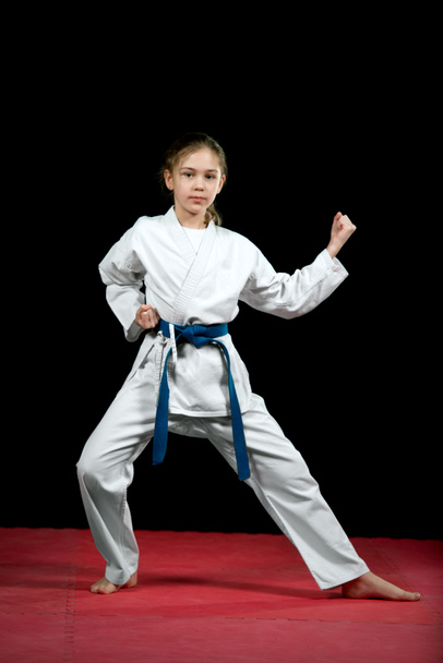 One little girl in white kimono during training karate kata exercises  - Foto, imagen