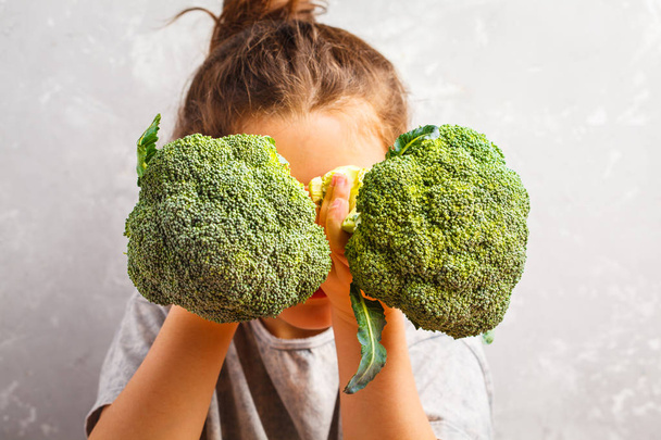 Little beautiful girl eating broccoli. Healthy vegan baby foods. - Foto, immagini
