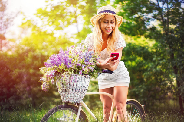 beautiful young girl with vintage bicycle and flowers on city background in the sunlight outdoor. - Foto, Imagen