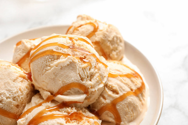 Tasty ice cream with caramel sauce on plate, closeup - Valokuva, kuva