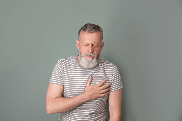 Mature man having heart attack on color background - Foto, Imagen
