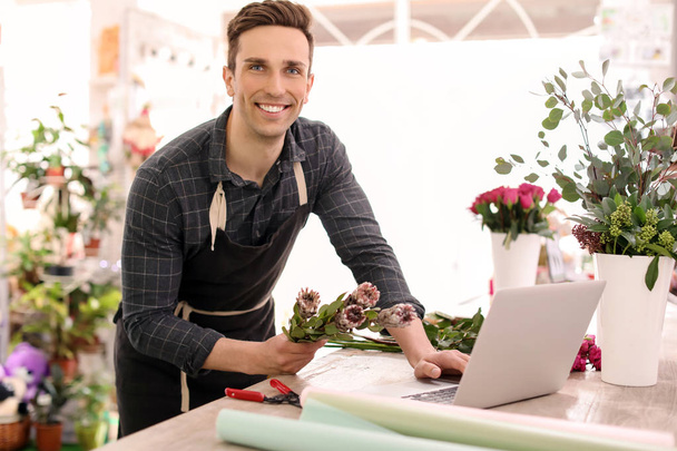 Young florist working with laptop in flower shop - 写真・画像