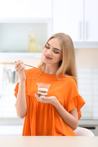 Jonge vrouw met yoghurt in keuken - Foto, afbeelding