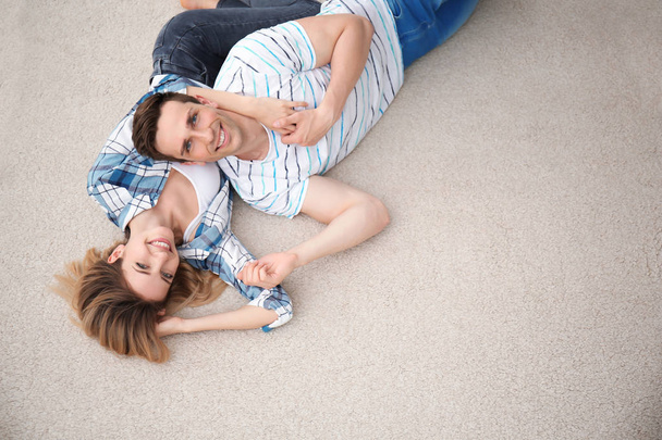 Preciosa pareja joven acostada en una alfombra acogedora en casa
 - Foto, Imagen