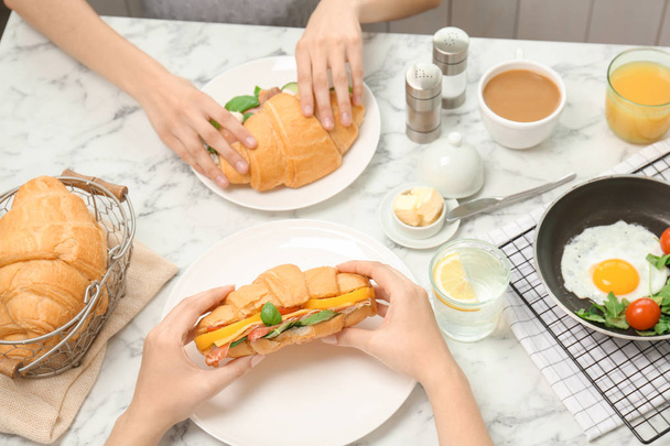 People eating tasty croissant sandwiches at table - Φωτογραφία, εικόνα