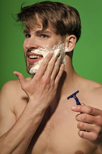 Happy man shave beard with razor on green background - Zdjęcie, obraz