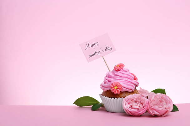 Tasty cupcake and flowers for Mother's Day on color background - Photo, Image