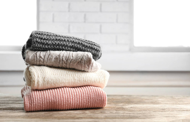 Stack of warm knitted clothes on table - Foto, Imagen
