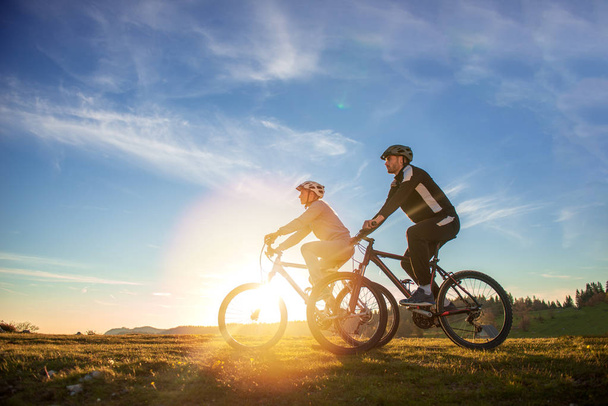 Happy mountainbike couple outdoors have fun together on a summer afternoon sunset - Foto, Imagem