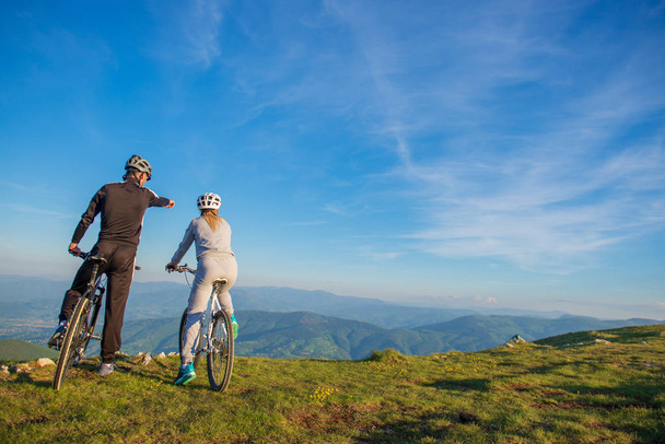 Radfahrerpaar mit Mountainbike zeigt in die Ferne - Foto, Bild
