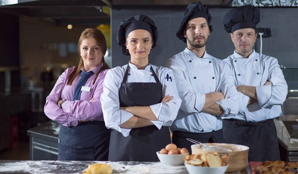 Portrait of group chefs standing together in commercial kitchen at restaurant - 写真・画像
