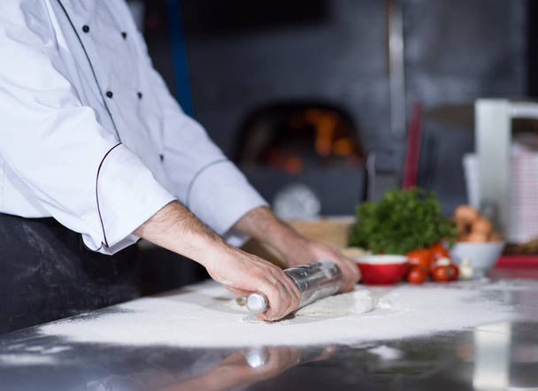 chef preparing dough for pizza with rolling pin - Foto, Bild