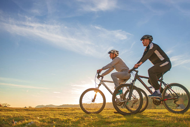 Happy mountainbike couple outdoors have fun together on a summer afternoon sunset - Fotó, kép