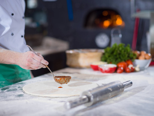 Chef smearing pizza dough with ketchup - Foto, Bild