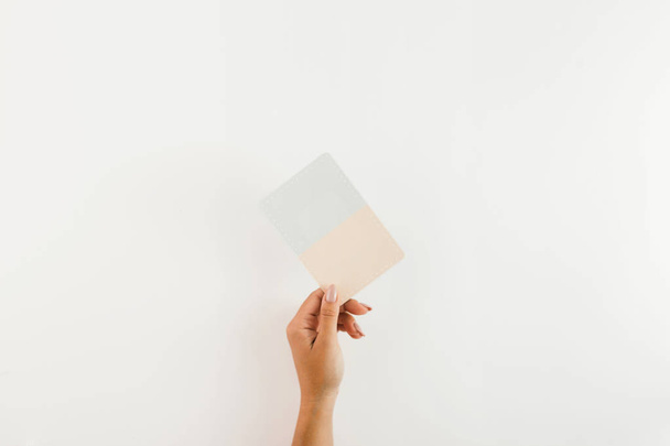 Woman hand holding card on white background. Flat lay, top view - Foto, afbeelding