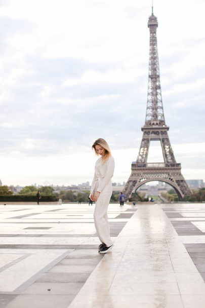 Stylish pretty woman standing near Eiffel Tower in white overalls. - Φωτογραφία, εικόνα