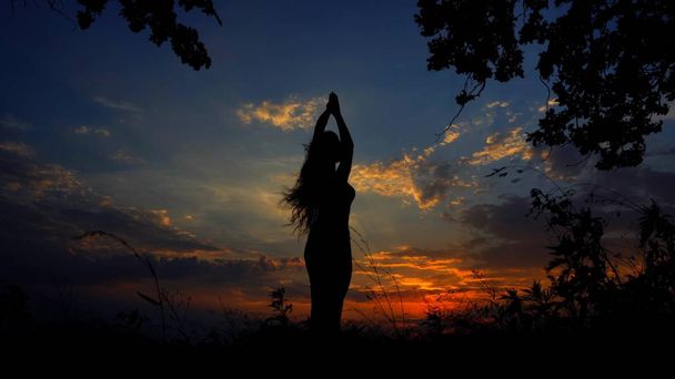 Nainen siluetti tekee jooga ja meditointi illalla taivaalla tausta
. - Valokuva, kuva