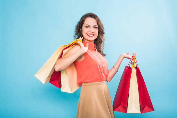 Mujer joven con bolsas de compras sobre fondo azul
 - Foto, imagen