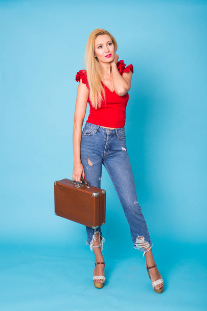 夏、ファッション、休日のコンセプト - 青の背景にレトロなスーツケースの金髪美女 - 写真・画像
