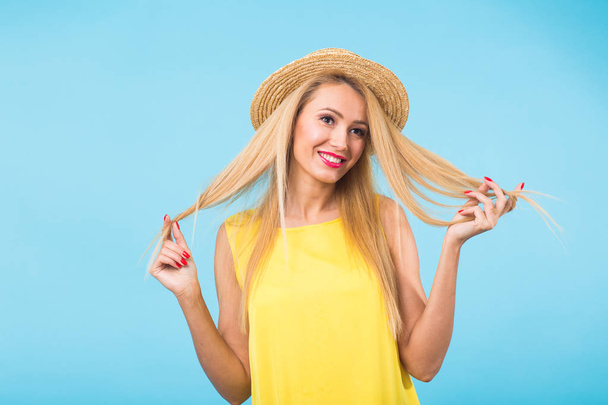 Portret van lachende blonde vrouw in modieuze blik op blauwe achtergrond. Stijl, fashion, zomer en mensen concept - Foto, afbeelding