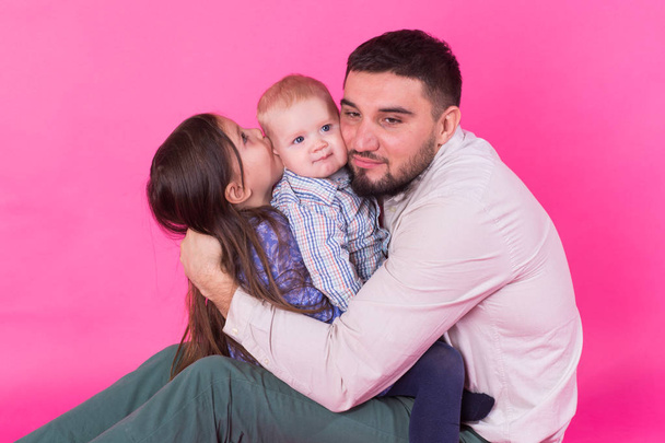 przystojny ojca, niosąc jego młodszy syn córka i dziecko na różowym tle - Zdjęcie, obraz