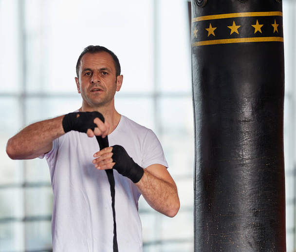 Kickbox fighter training with heavy bag in the gym - Fotó, kép