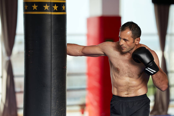 Kickbox fighter training with heavy bag in the gym - Foto, Imagen