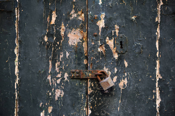 Puinen tummanharmaa oven tausta lukittu ruosteisella riippulukolla. Ikääntynyt sisäänkäynti, lähikuva yksityiskohtia
. - Valokuva, kuva