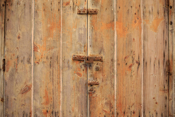 Волнистый коричневый фон двери, запертой ржавым замком. Закрытый дверной проем, закрытый вид с подробной информацией
. - Фото, изображение