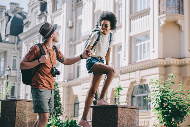 mannelijke reiziger met camera die hand van Afro-Amerikaanse vriendin  - Foto, afbeelding
