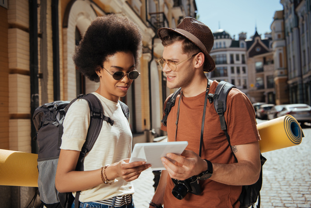 junges multiethnisches Touristenpaar mit Kamera und digitalem Tablet  - Foto, Bild