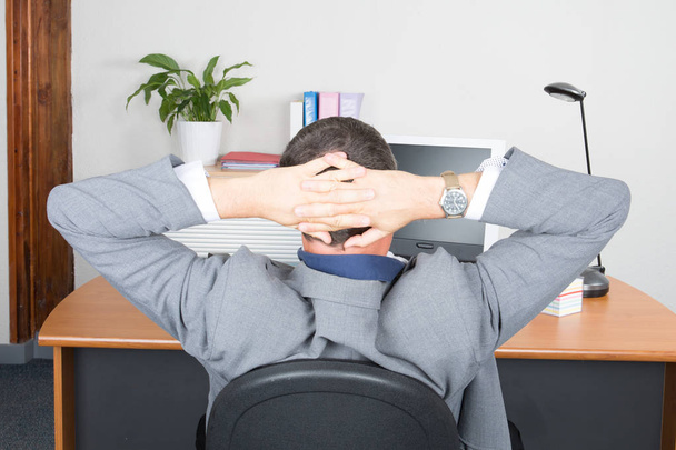 businessman relaxing with hands behind head at office desk - Zdjęcie, obraz