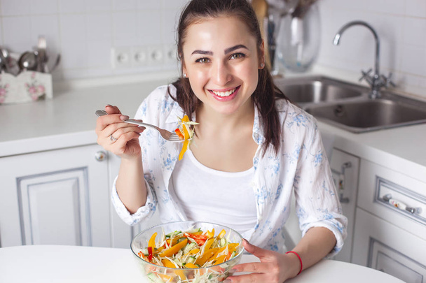 Gezonde jonge vrouw salade eten op de keuken - Foto, afbeelding