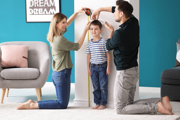 Parents measuring height of their son at home - Φωτογραφία, εικόνα