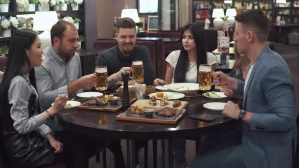 gruppo multietnico di amici che cenano in un caffè. una grande azienda divertirsi insieme, ridere e parlare. gli uomini battono gli occhiali
 - Filmati, video