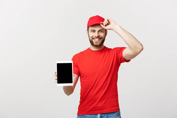 Online shopping, delivery, technology and lifestyle concept - smiling delivery man presenting tablet in his hand showing something. Isolated over white studio background. - Foto, immagini