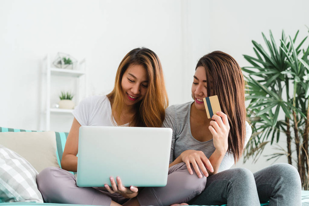 Beautiful young asian women LGBT lesbian happy couple sitting on sofa buying online using laptop a computer and credit card in living room at home. LGBT lesbian couple together indoors concept. - Foto, Imagen