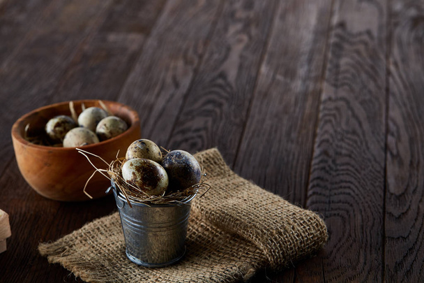 Rustic still life with quail eggs in bucket, box and bowl on a linen napkin over wooden background, selective focus - Foto, immagini
