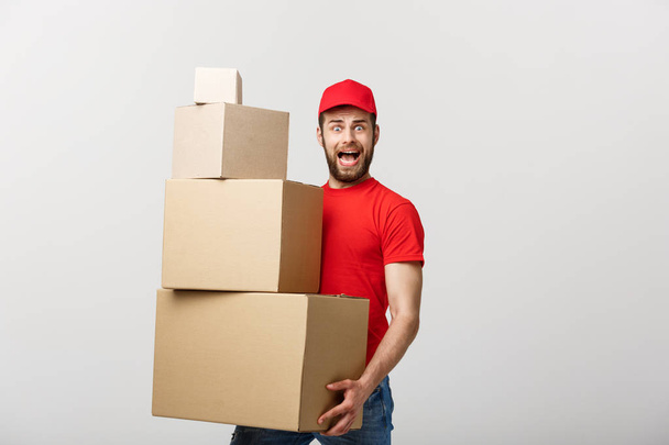 Delivery man doing surprise gesture holding cardboard boxes. - Photo, Image