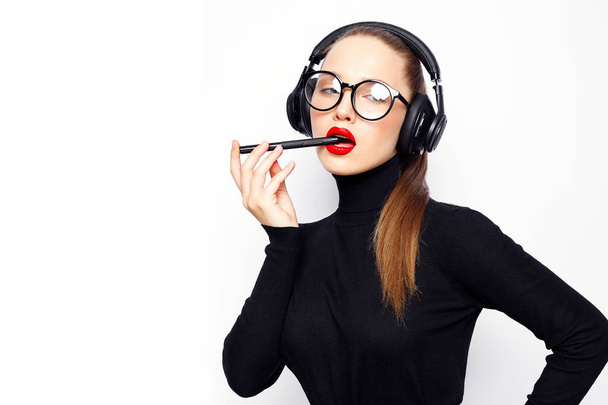 Young woman in headphones and red lips posing against white background - Foto, Imagem