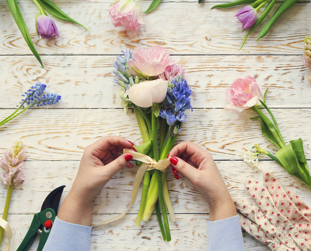 Florist bei der Arbeit. Frau macht Blumenstrauß aus Frühlingsblumen - Foto, Bild