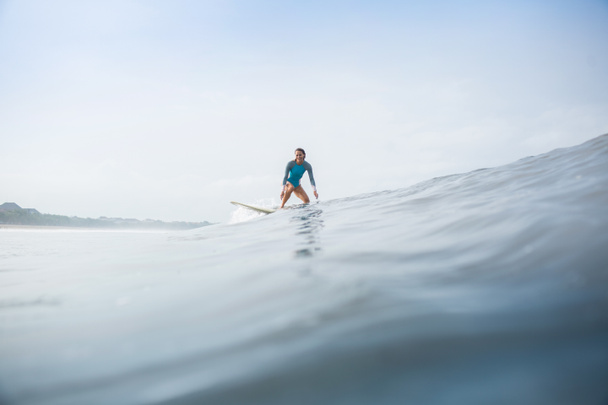 giovane donna in costume da bagno sportivo cavalcare tavola da surf in oceano
 - Foto, immagini