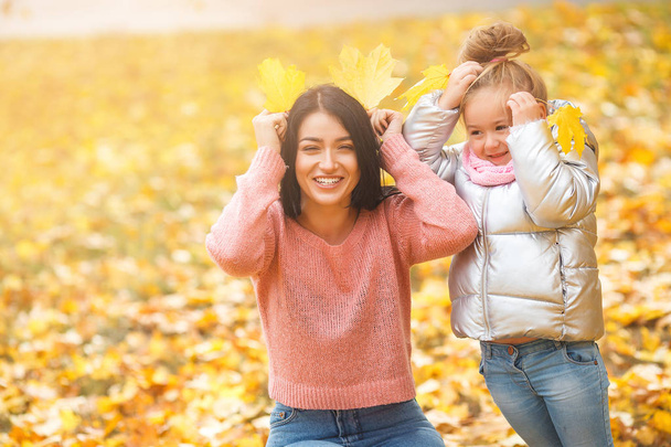 Neşeli kızlar sarı yaprakları ile oynuyor. Mutlu anne ve eğleniyor sonbahar zamanla küçük çocuk - Fotoğraf, Görsel