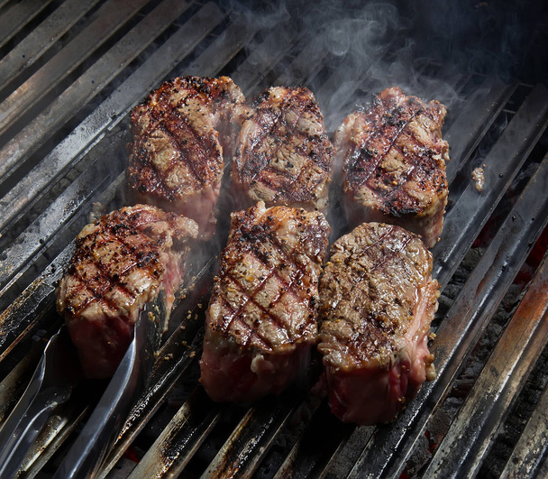 Steaks with spices on hot grill. Food background. - Photo, Image